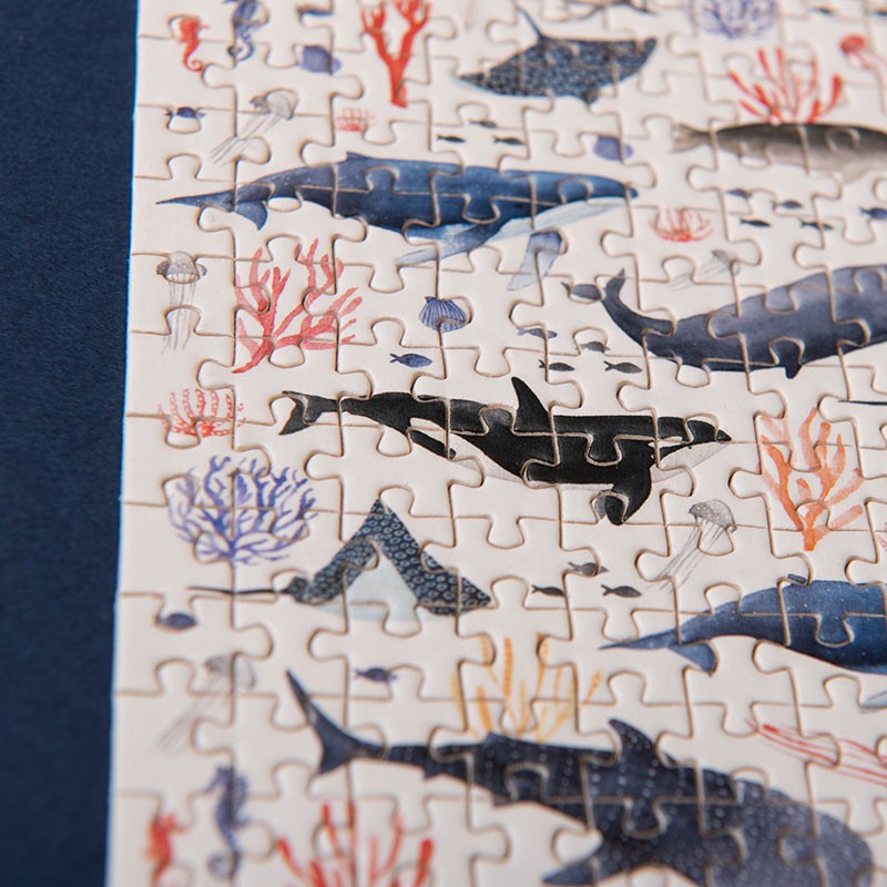 150-piece-micro-puzzle-whales Close-up of a partially completed puzzle with ocean-themed design featuring sharks and corals.