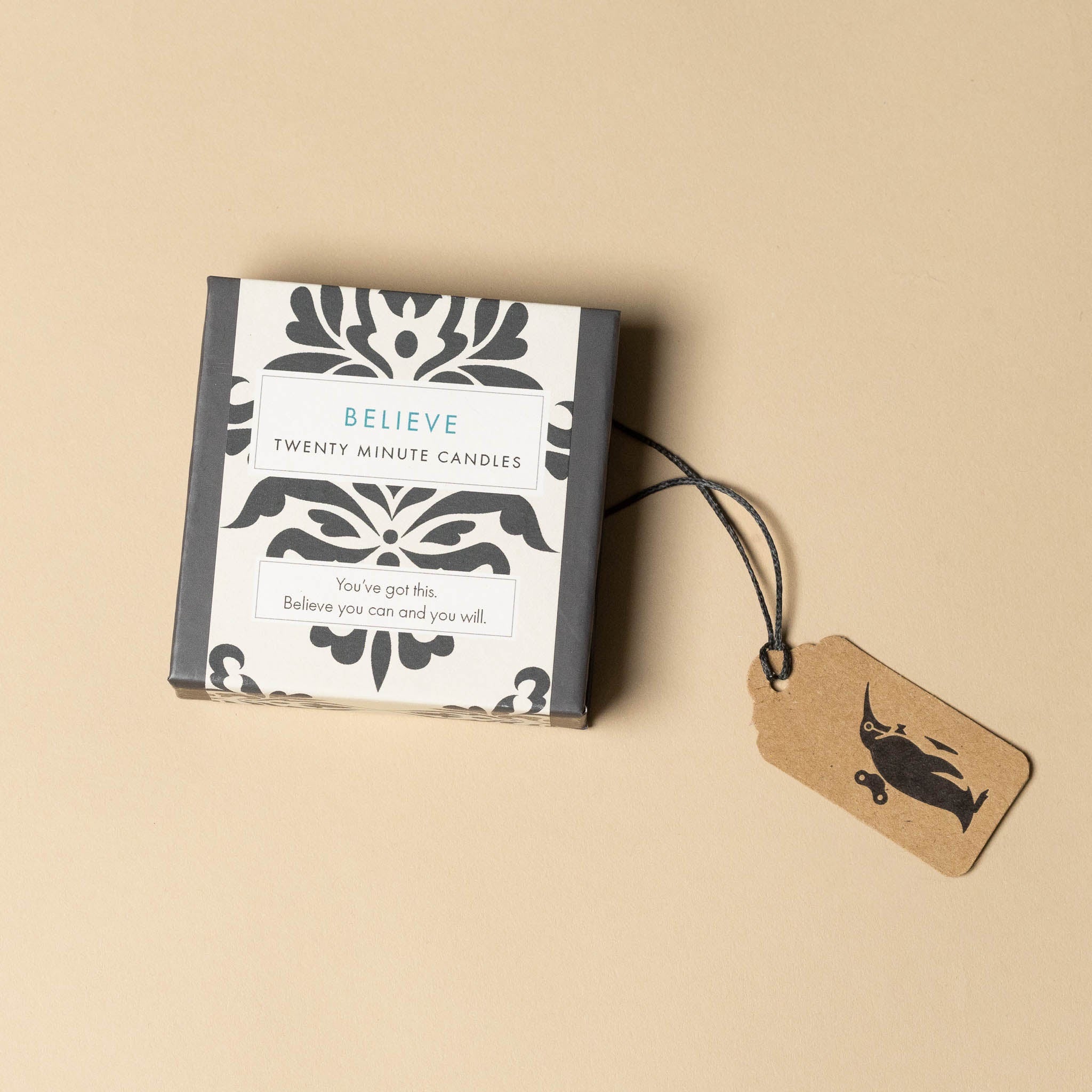 Box of 'Believe' twenty-minute candles with a tag on a beige background