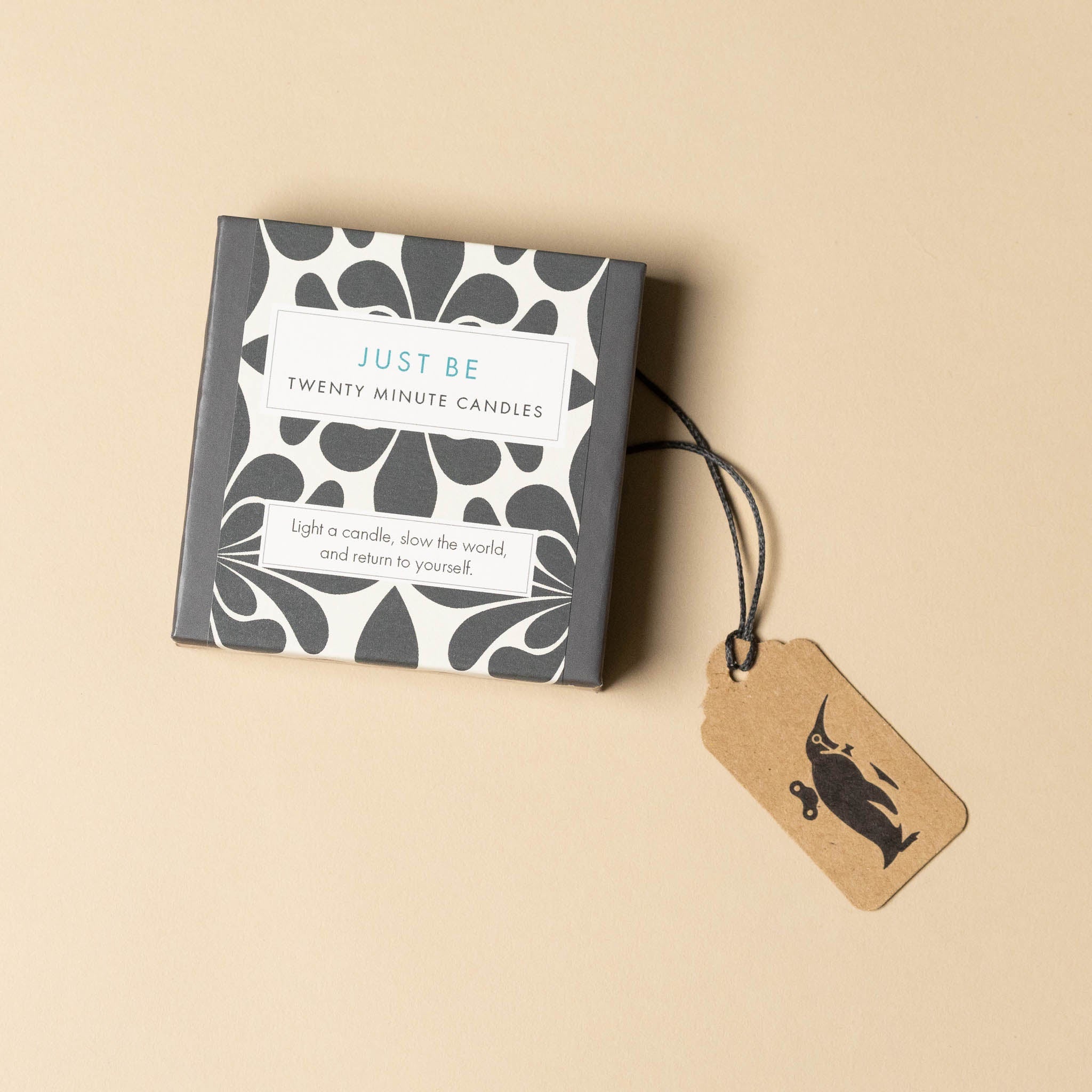 Box of 'Just Be' twenty-minute candles with a tag on a beige background