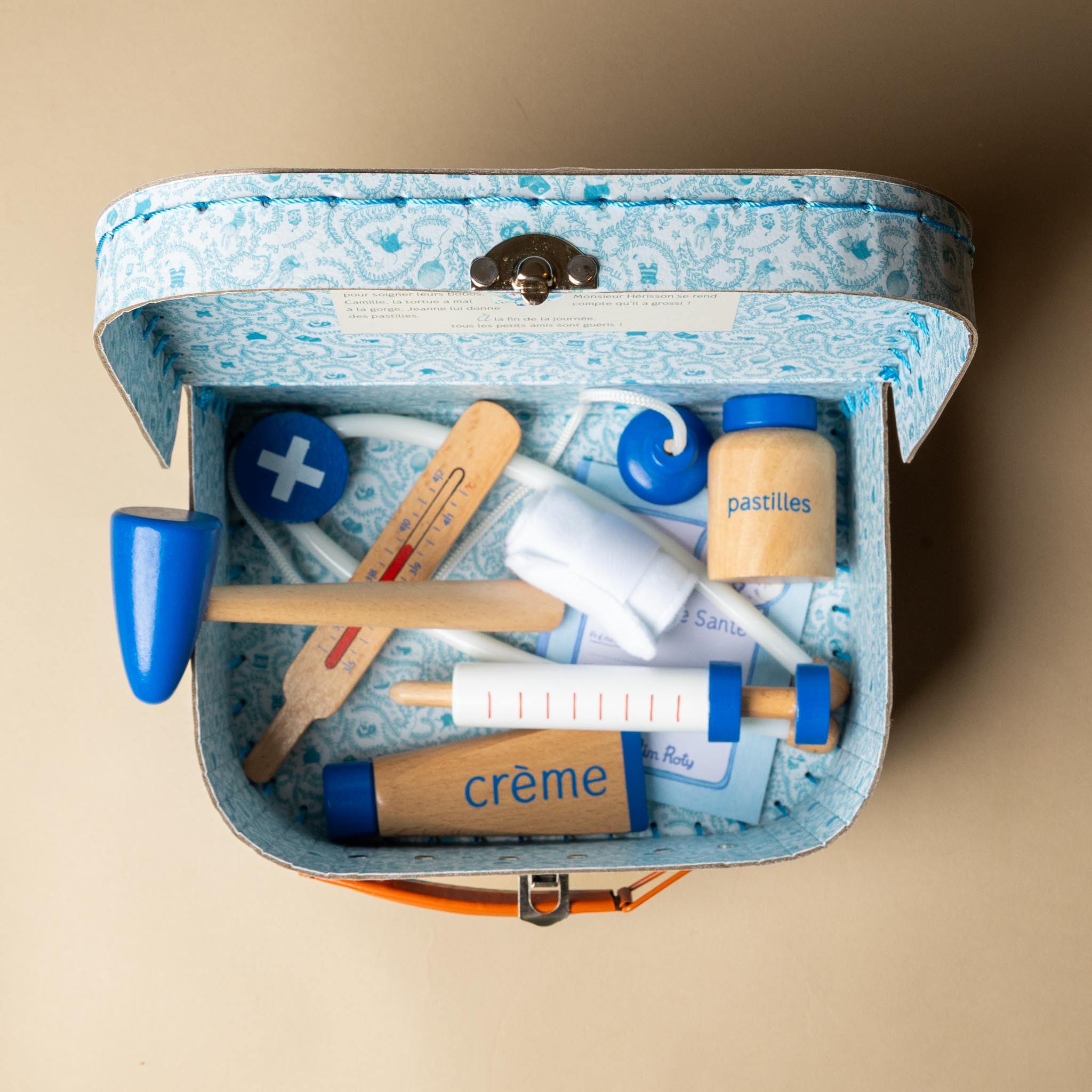 La-Grande-Famille-Doctor-Valise Open vintage first aid kit with various items on a beige background