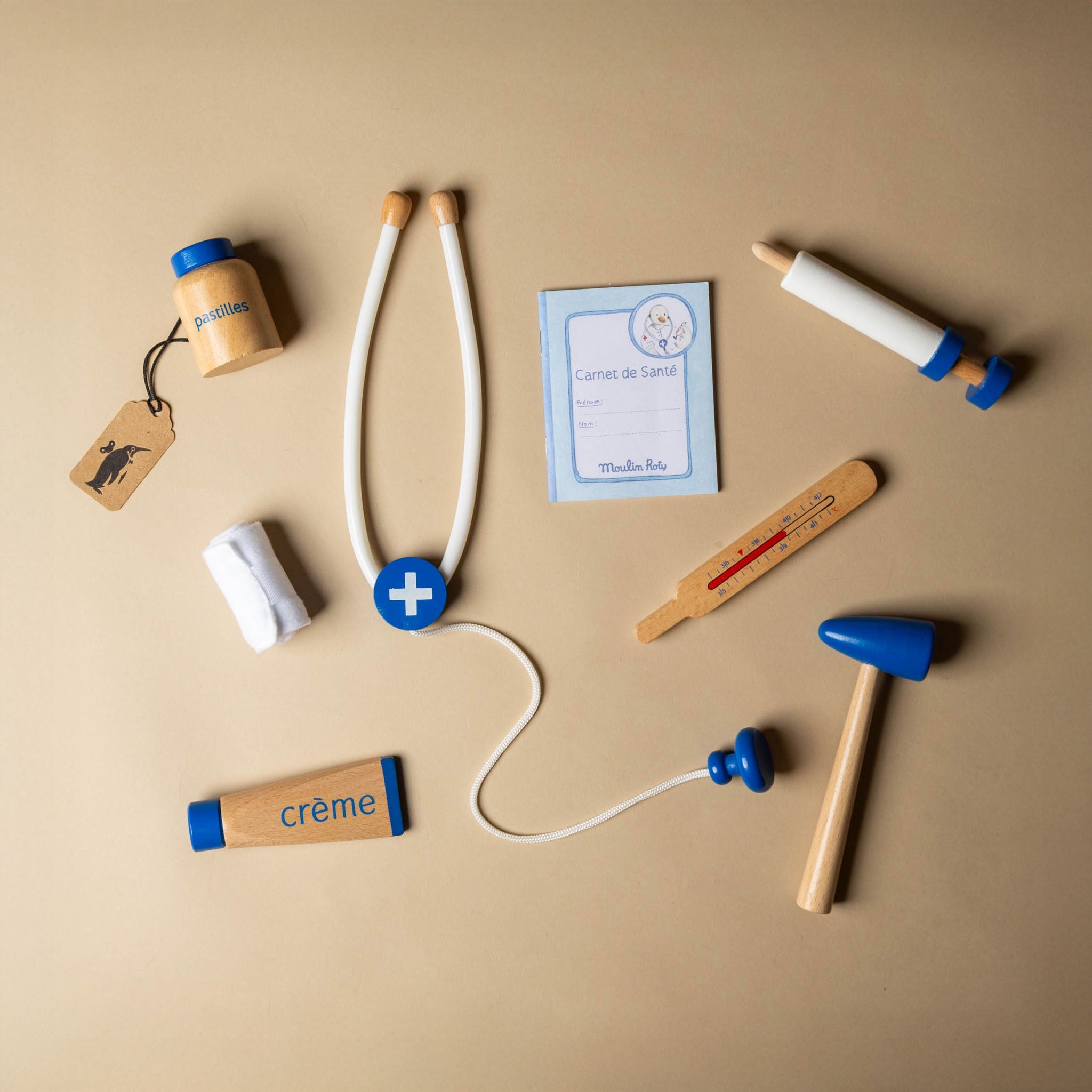 La-Grande-Famille-Doctor-Valise Collection of wooden toys resembling medical supplies on a beige background