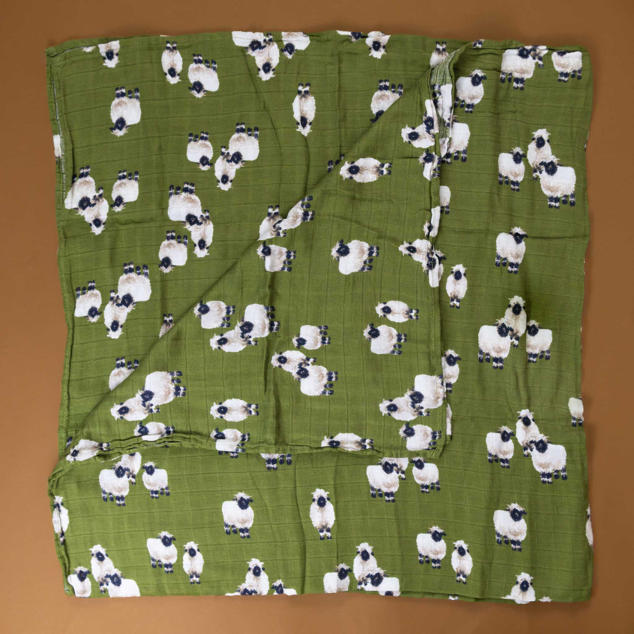 bamboo-swaddle-valais-sheep-green-background-with-black-and-white-sheep