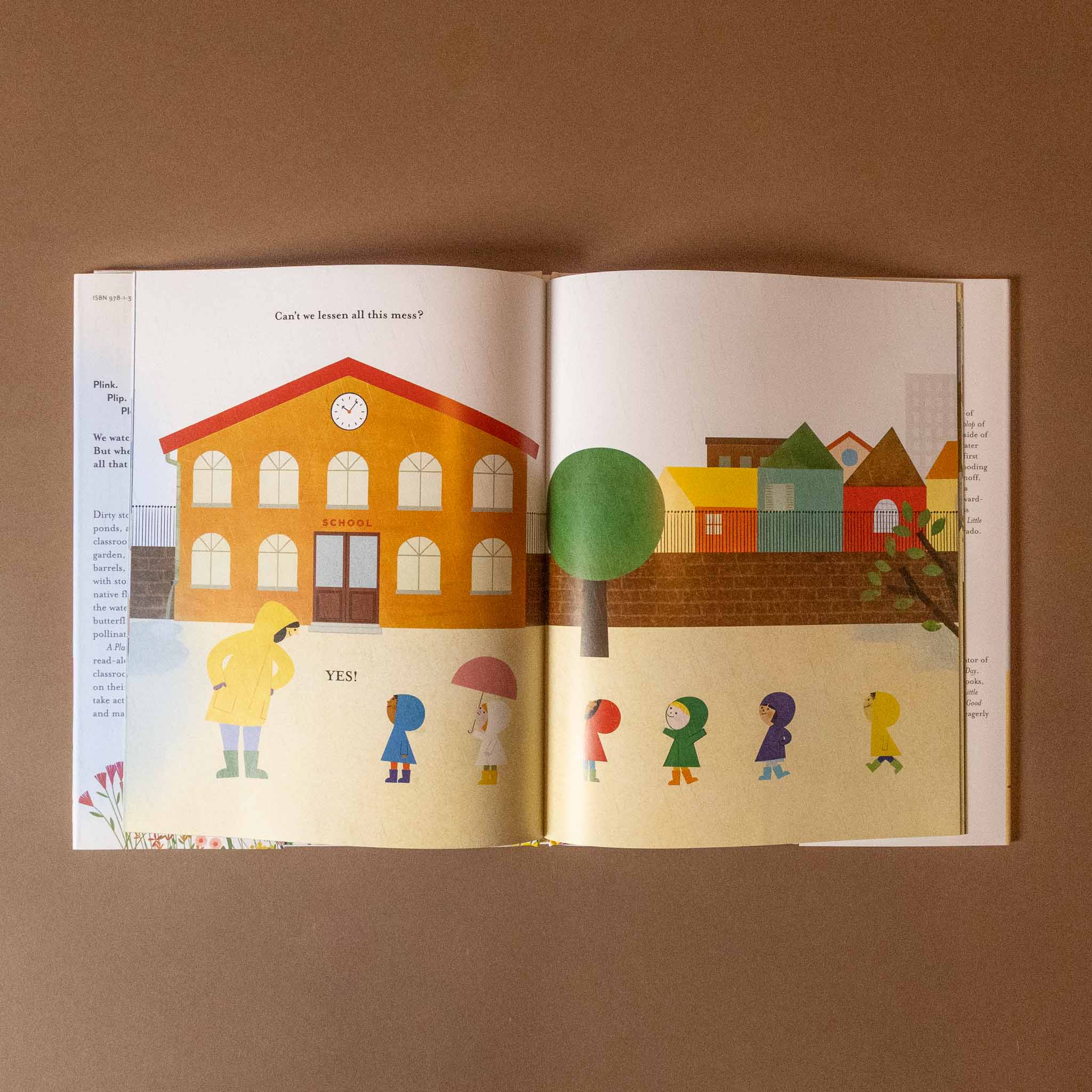Open a-place-for-rain book with colorful illustrations of a school, tree, and children on a brown background