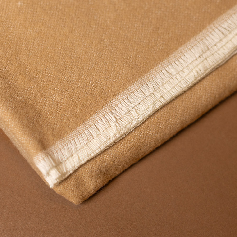 aspen-throw-latte Close-up of brown fabric with a fringe white border