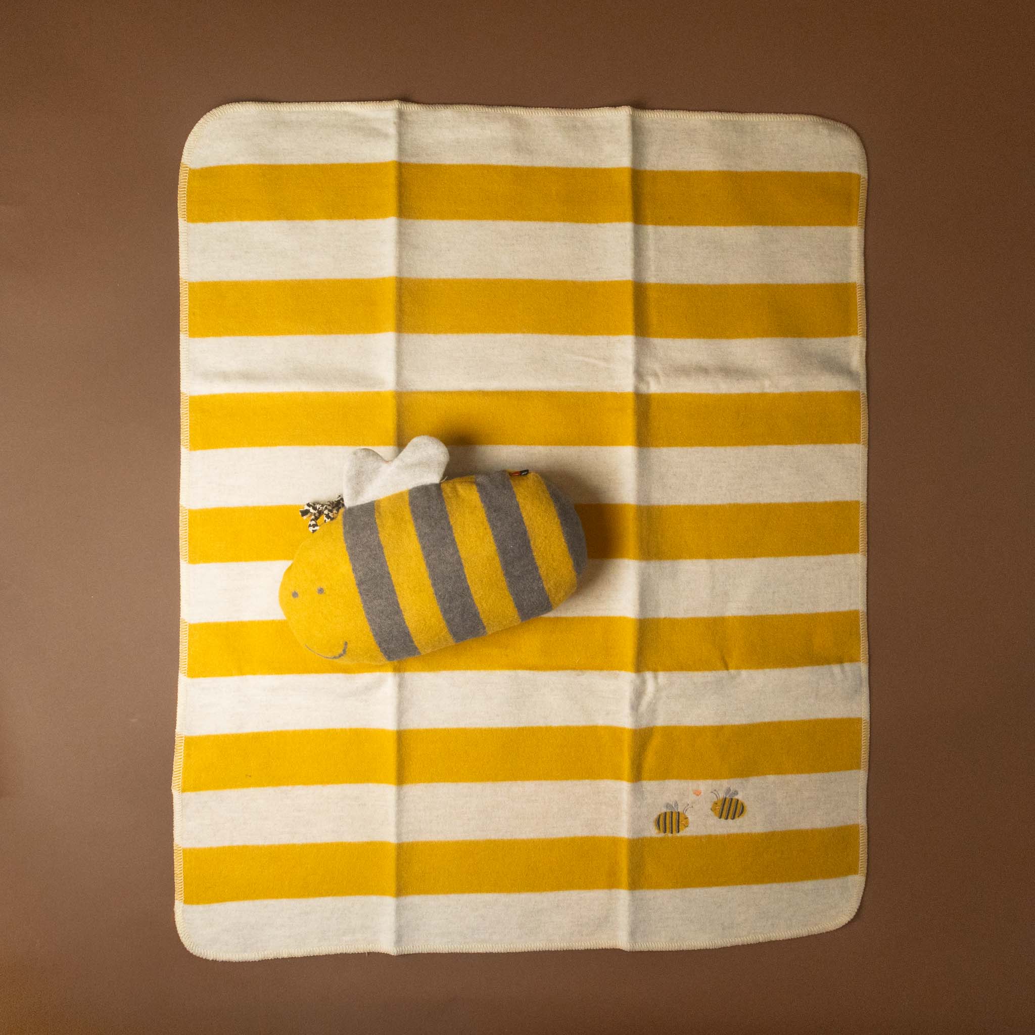 Yellow and white striped baby-blanket-embroidered-bumblebee with a bee design pillow on a brown background