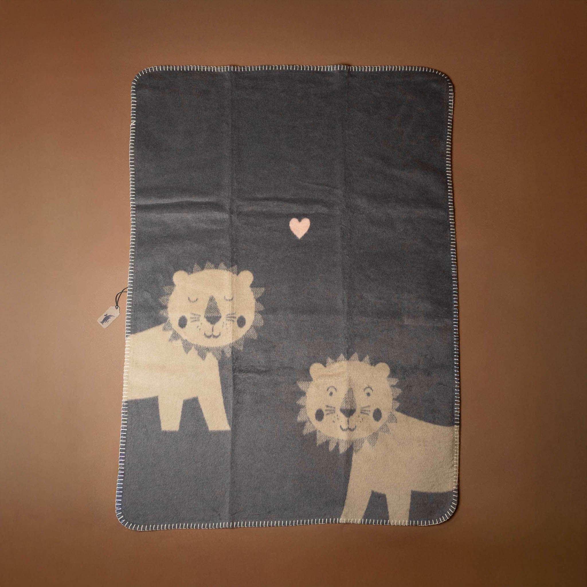 baby-blanket-sleepy-wakey-lions- Blanket with lion designs on a brown background