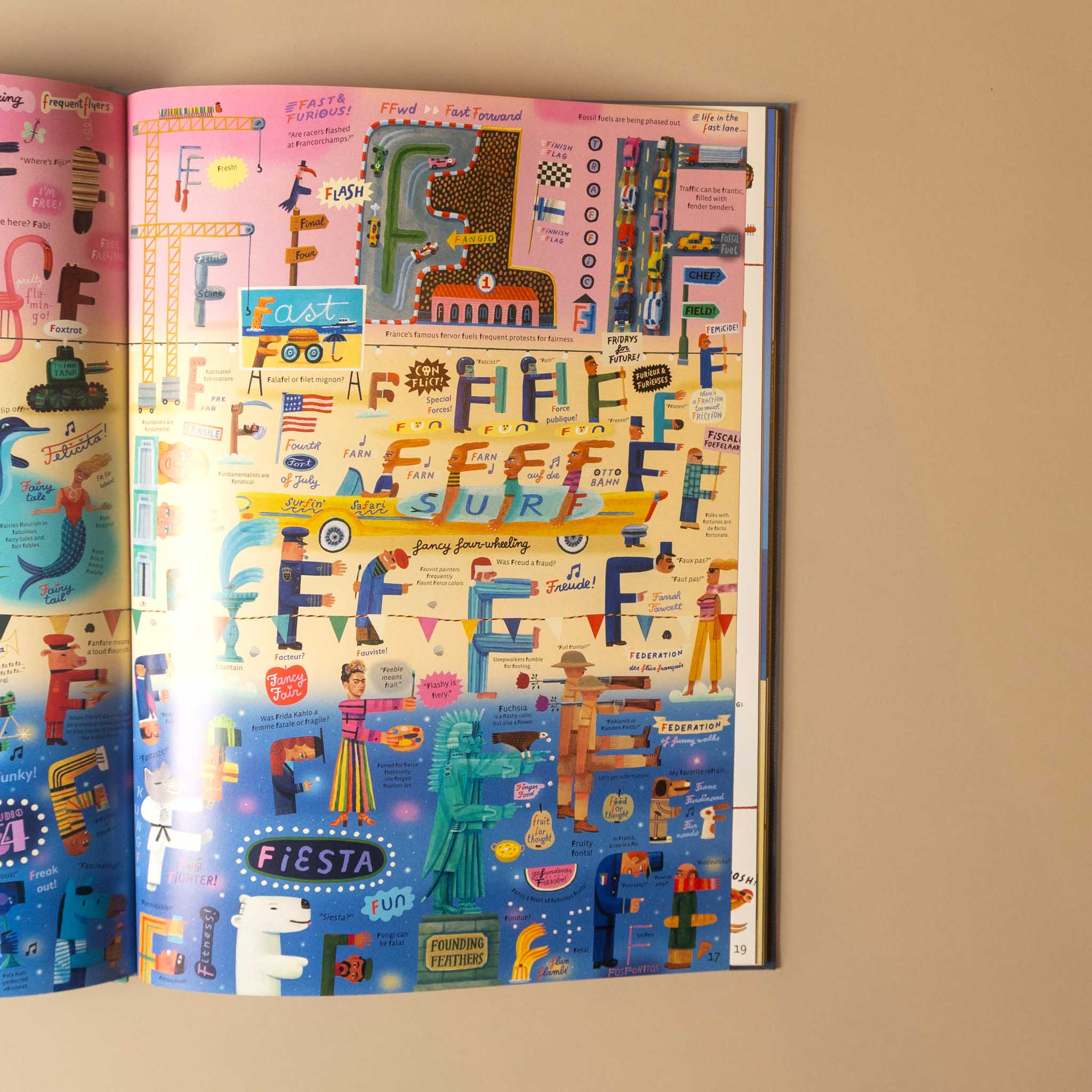 An open illustrated alphabet book spread against a beige wall, showing colorful letter illustrations and small decorative scenes across multiple pages.