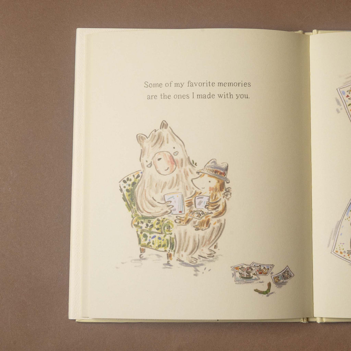 An open children's book lying flat on a brown surface, showing a cream-colored page with printed text and a watercolor-style illustration of a cat and mouse sitting together.