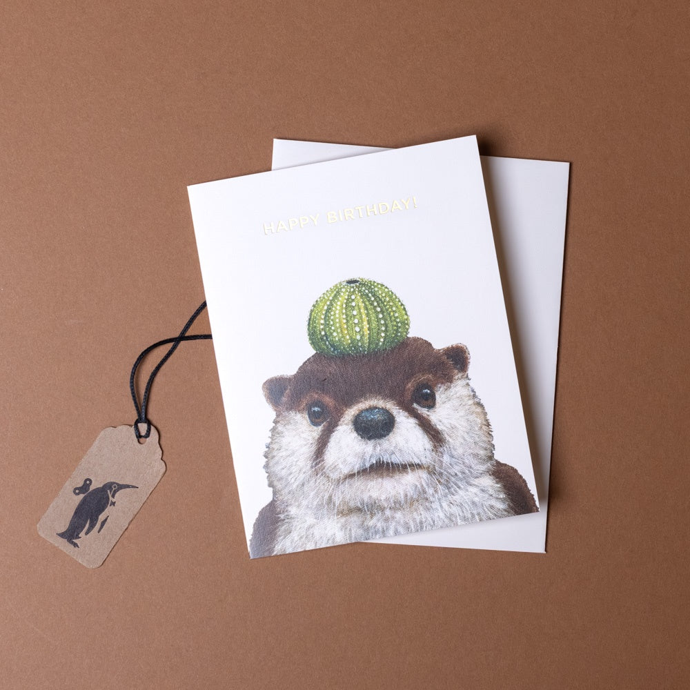 birthday-otter-greeting-card with an otter holding a cactus on a brown background