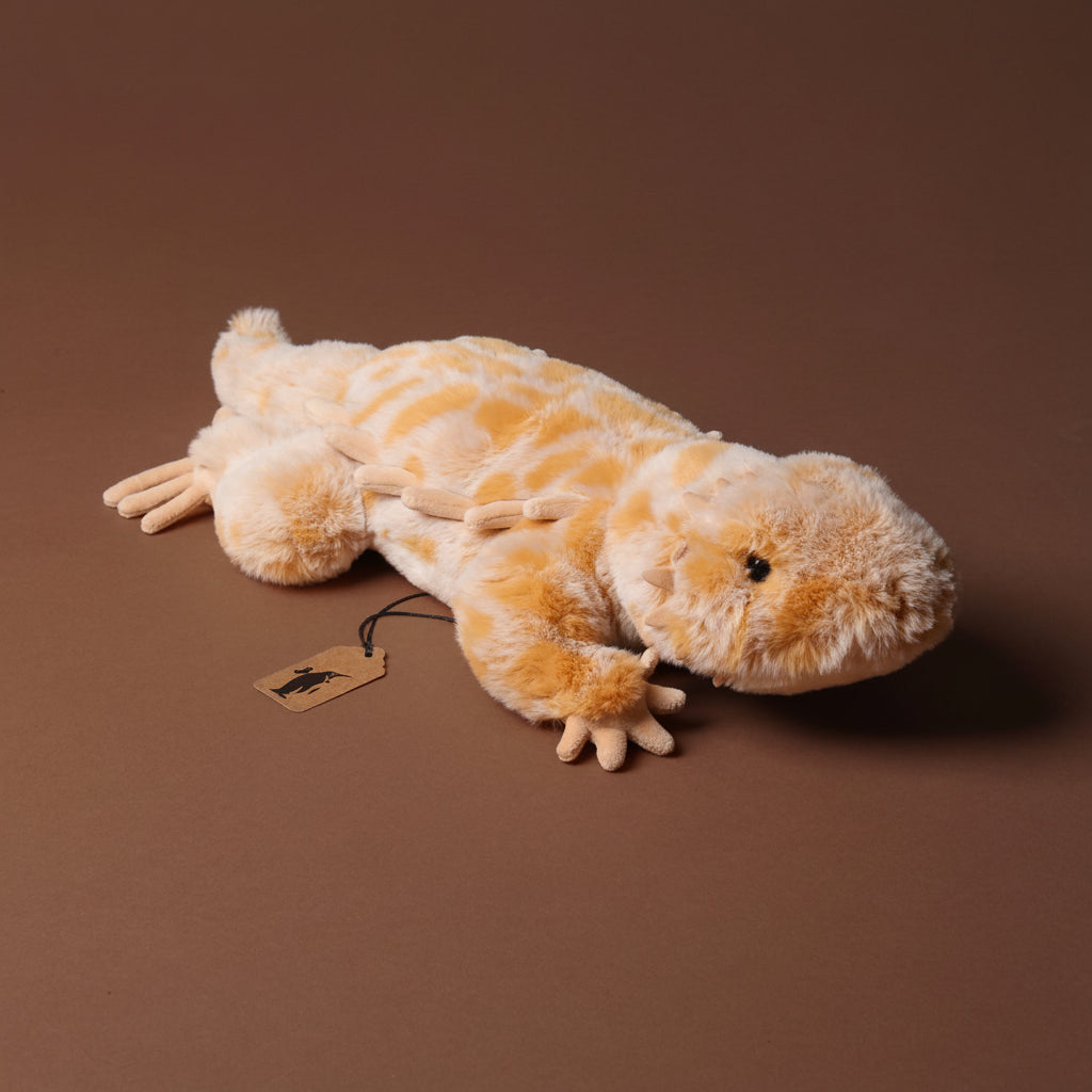 Plush toy boogie-the-bearded-dragon lizard on a brown background