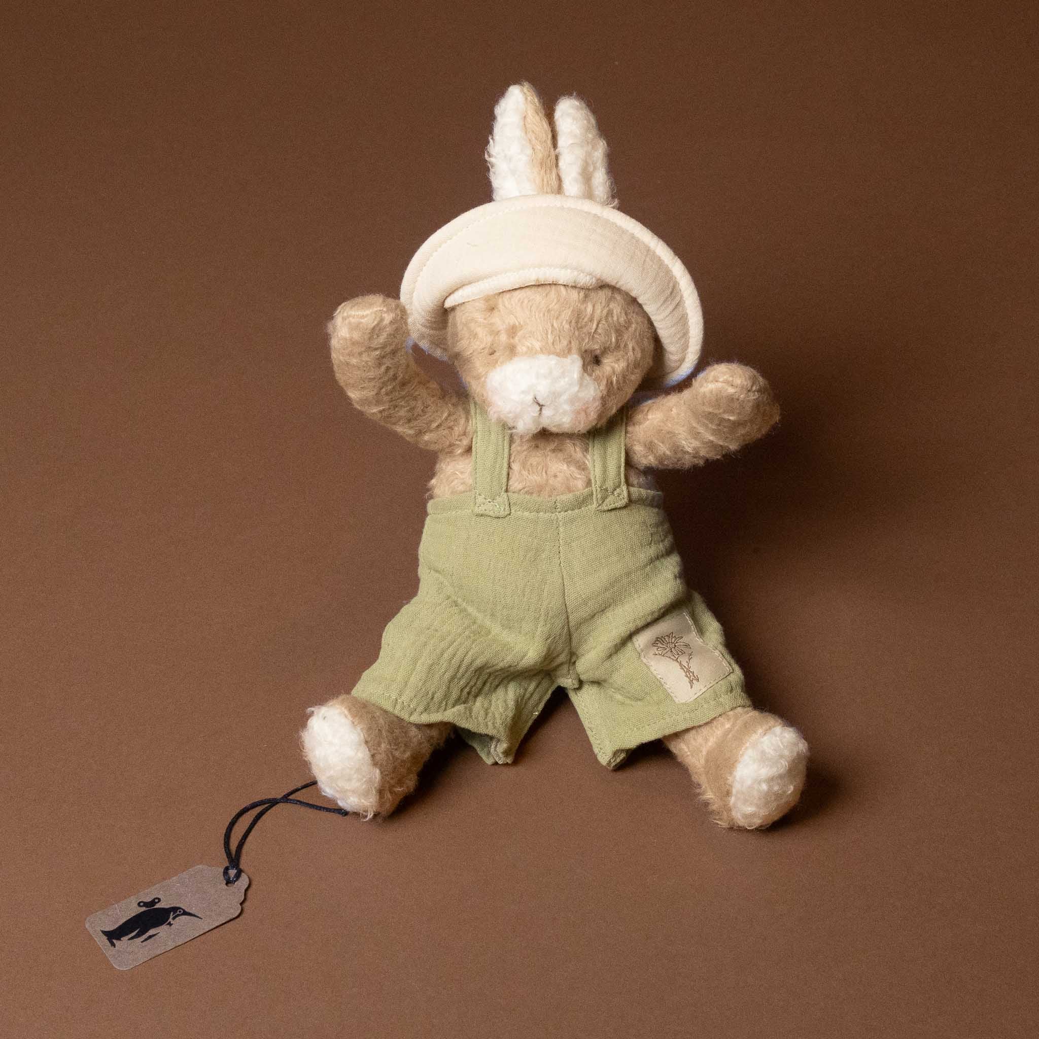 Stuffed bramble-the-bunny-limited-edition with green overalls and white hat on a brown background