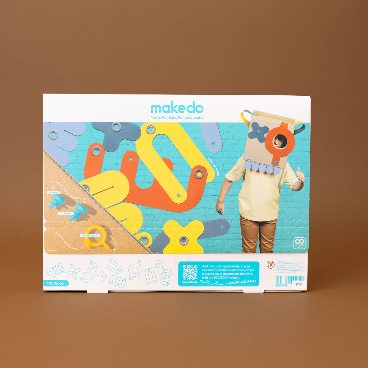 toy construction kit in its original retail box, displayed against a solid brown background. The packaging features a colorful illustration of gears, a wooden board, and a child wearing a cardboard robot head.