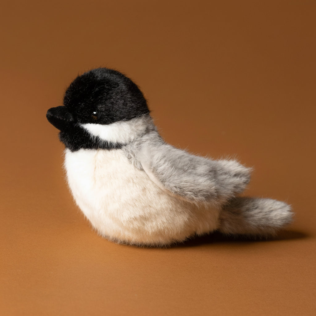Plush toy chipper-the-chicakdee- with a black head and gray body on a brown background
