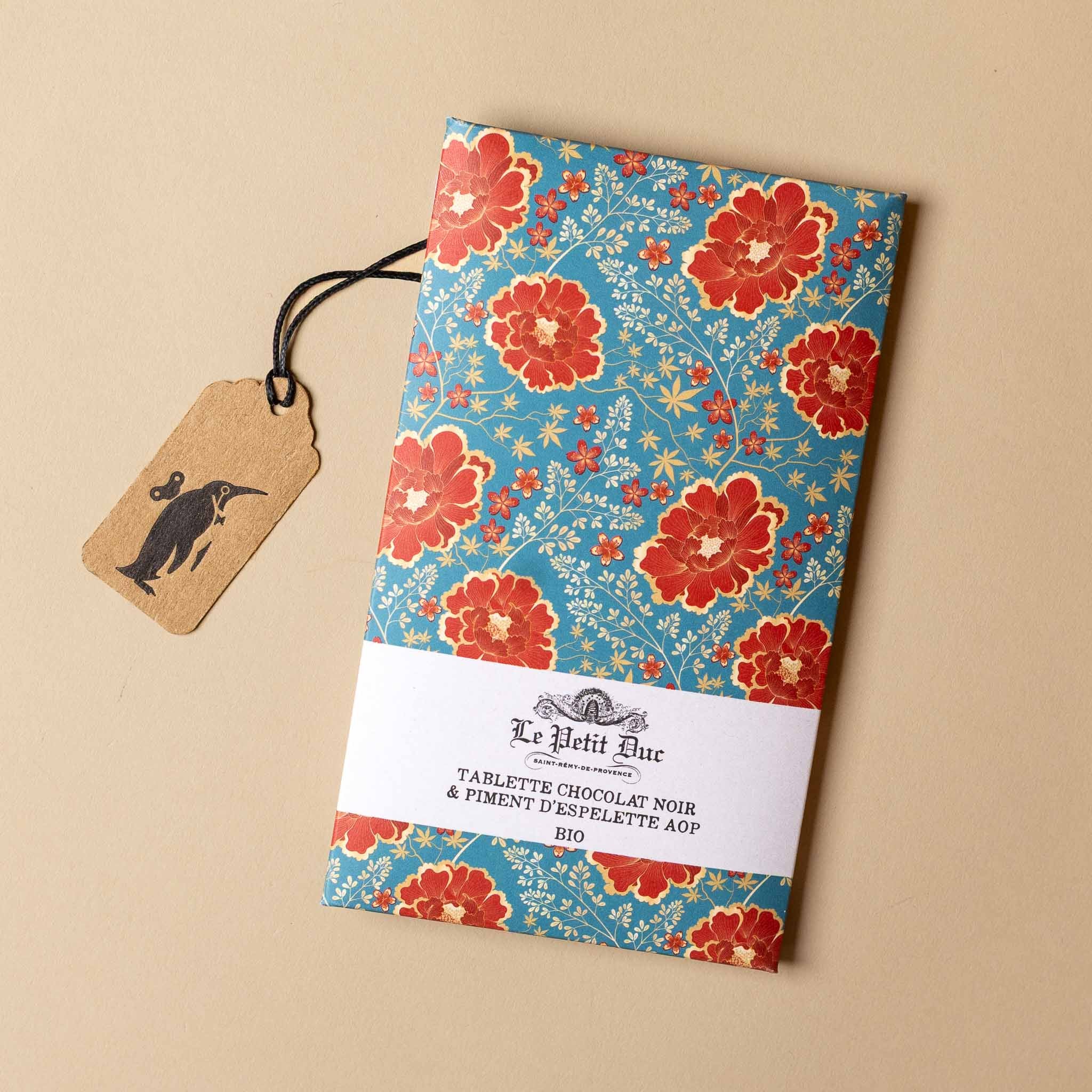 chocolat-noir-bar-espelette-pepper Floral-patterned product packaging with a tag on a beige background