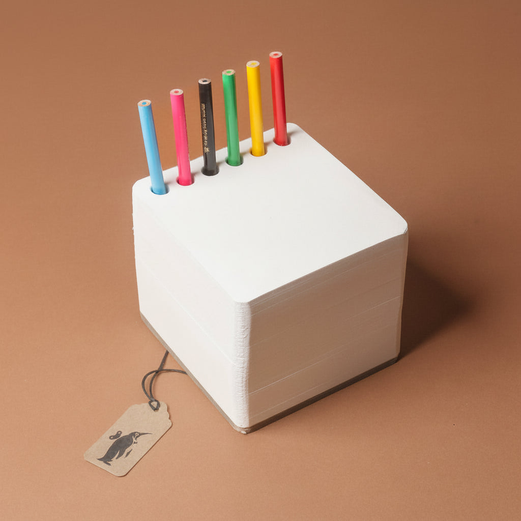 chunky-jotblock-sketch-pad-squared White cube with colorful pencils on a brown background