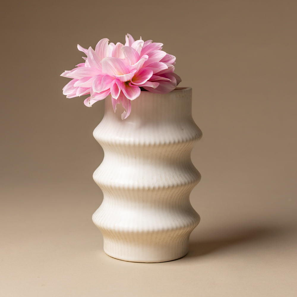 claude-bookend-vase-ripple White textured vase with a pink flower on a beige background