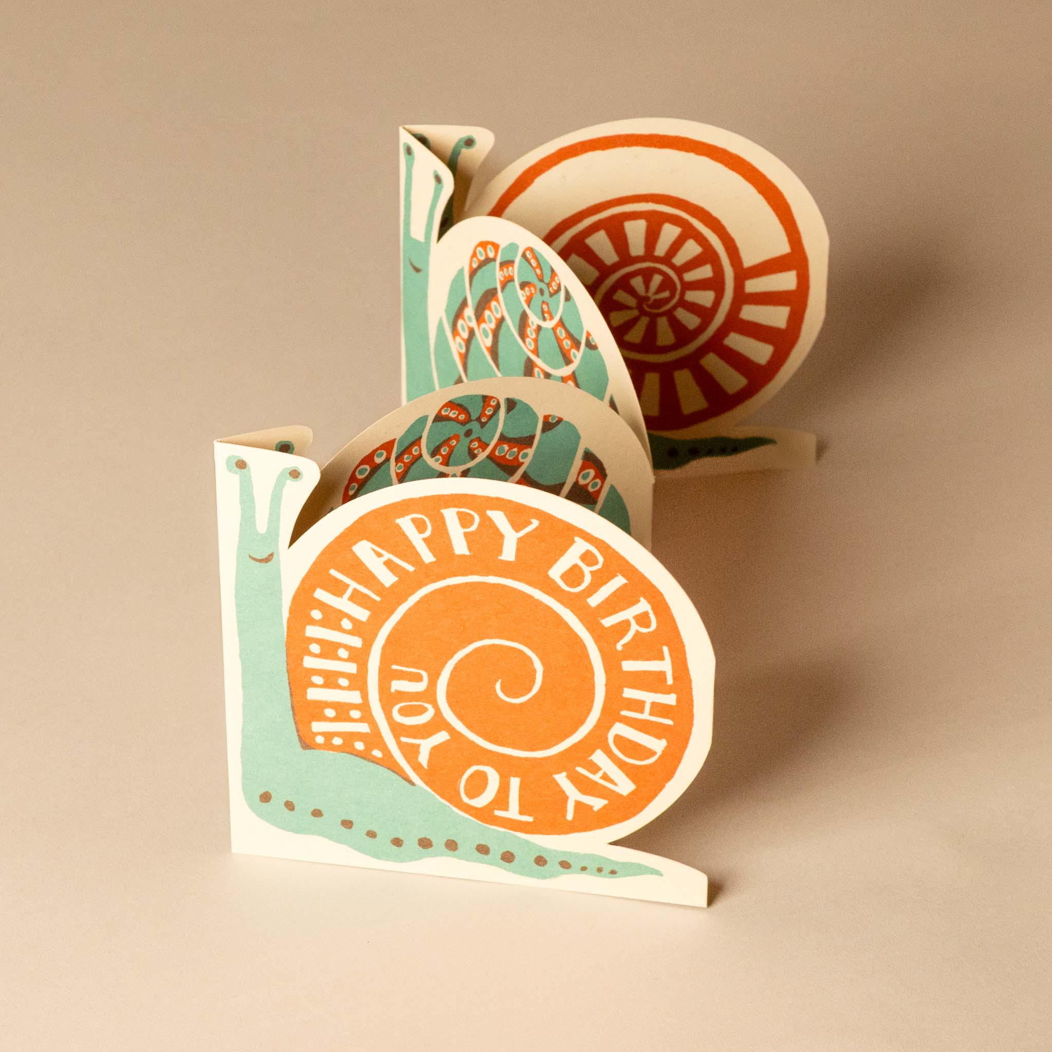 concertina-greeting-card--fold-out-birthday-snail with 'Happy Birthday' text and decorative elements on a beige background