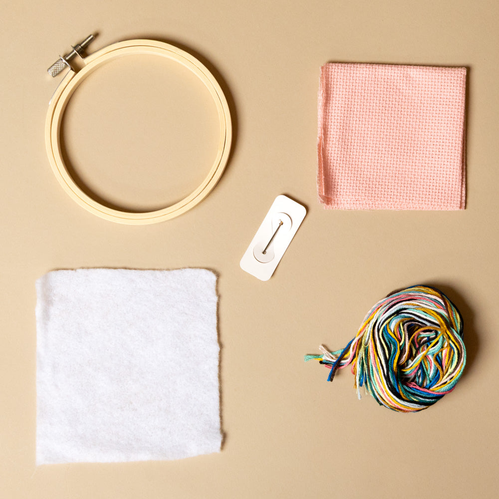 cross-stitch-kit-sardines Embroidery hoop, fabric, and yarn on a beige background