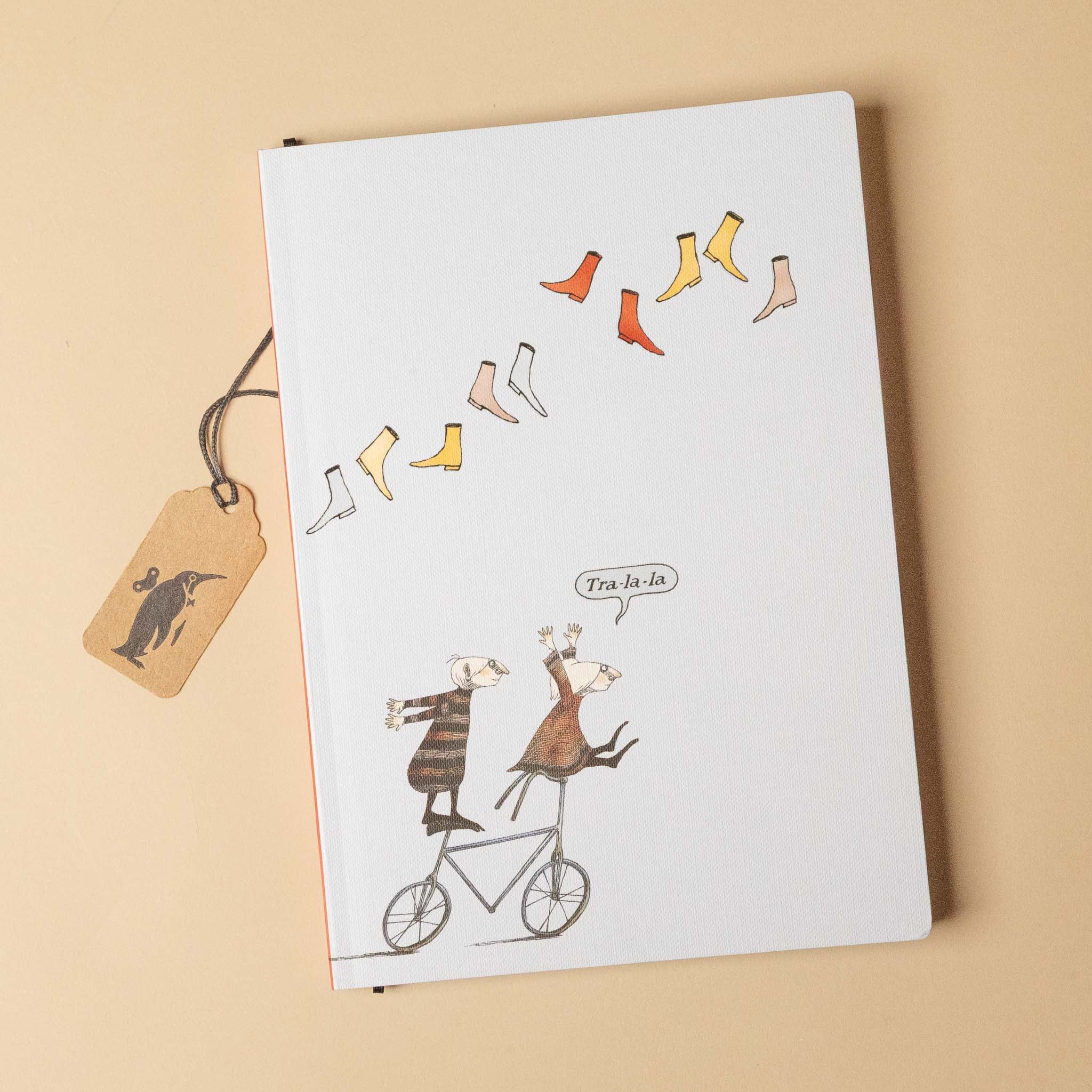 edward-gorey-journal-tra-la-la Notebook with illustration of two animals on a bicycle and socks hanging from a string on a beige background