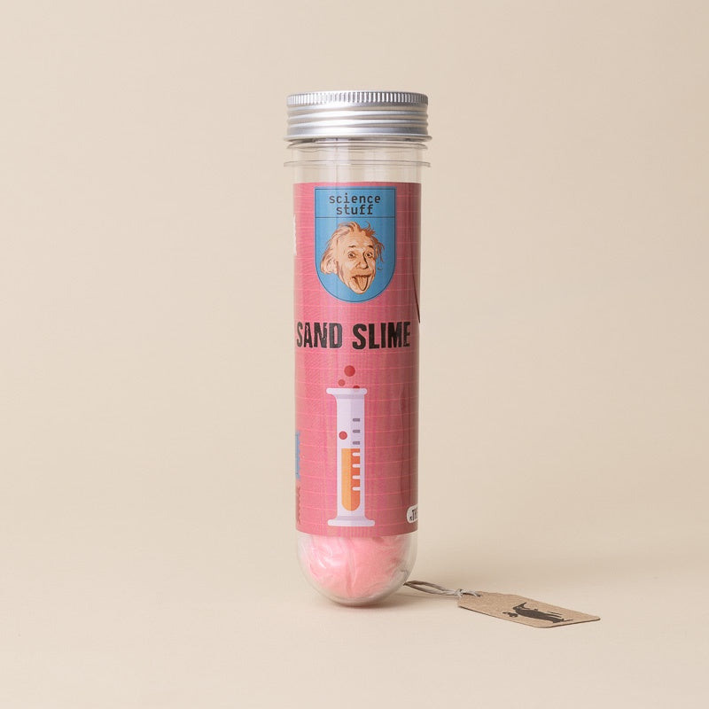 A clear cylindrical tube with a silver metal lid containing pink sand slime, wrapped in a pink label that reads 'science stuff sand slime' with an illustration of Albert Einstein. A small paper tag hangs from the base on a plain beige background.