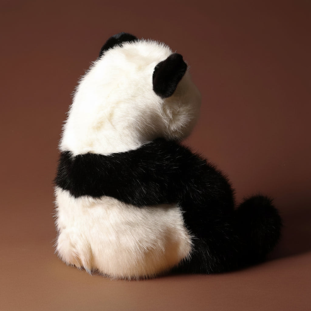 Plush emmet-the-panda-bear toy on a brown background
