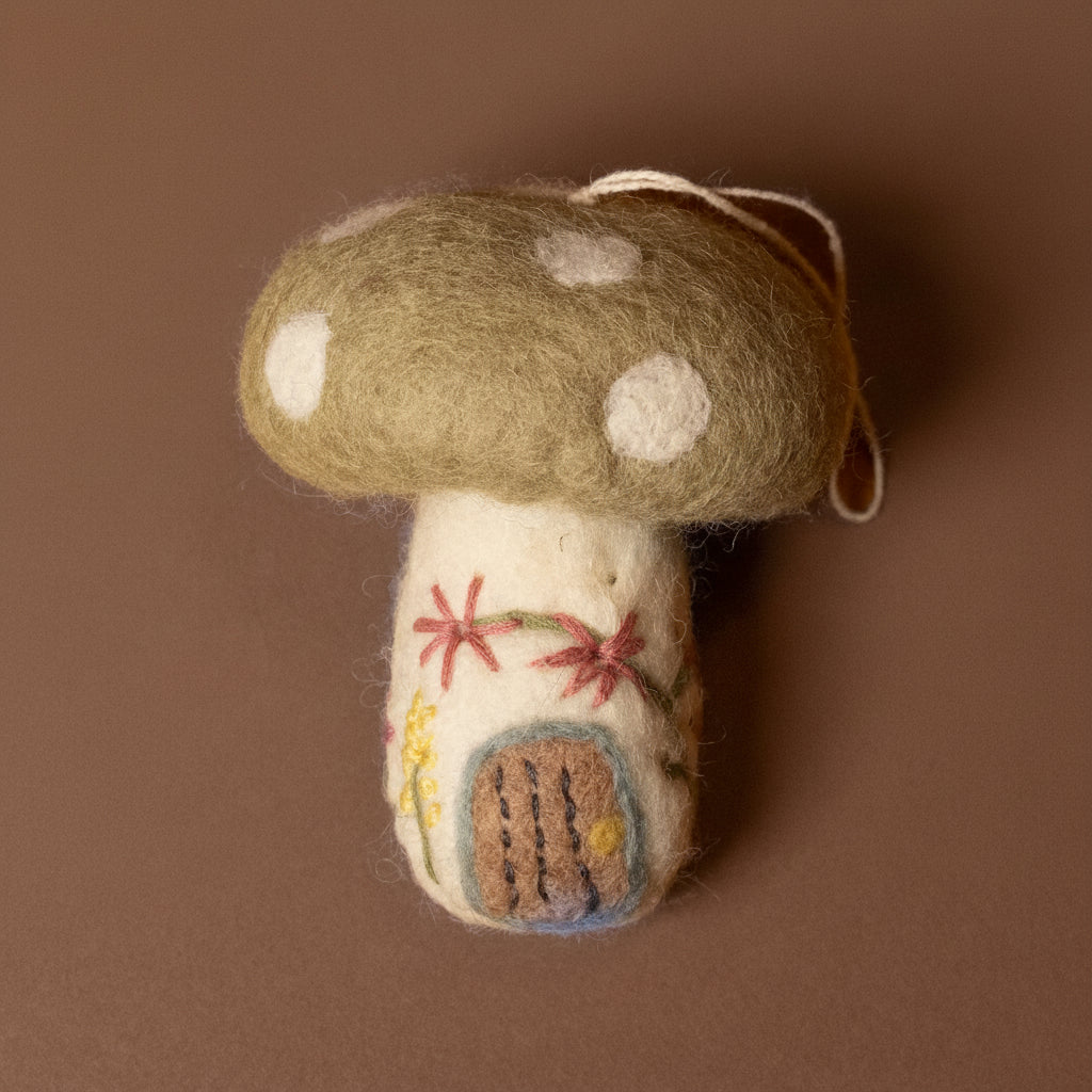 Felted mushroom ornament with embroidered details on a brown background