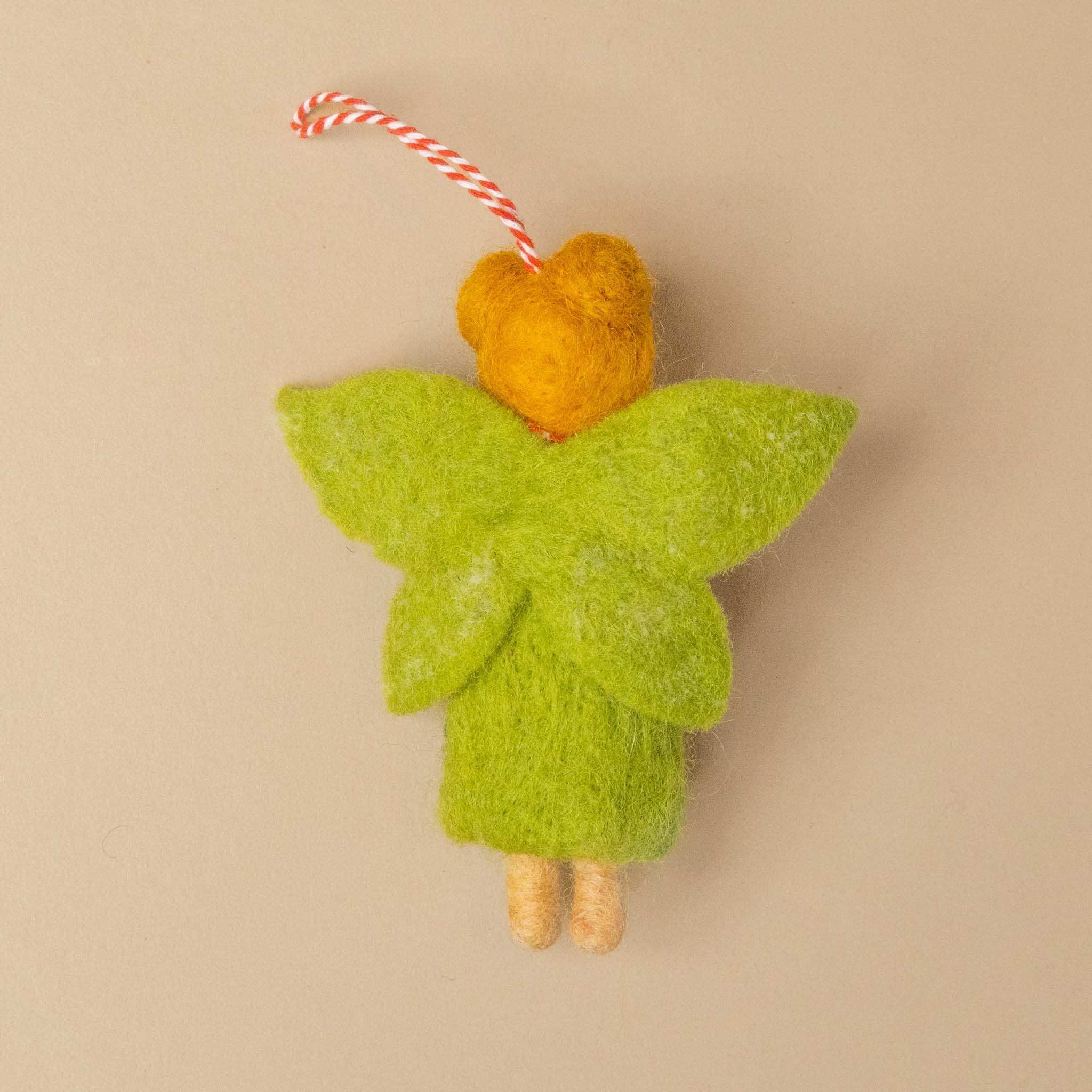 felted-garden-fairy-mossy-fleurornament with a heart-shaped wings on a beige background