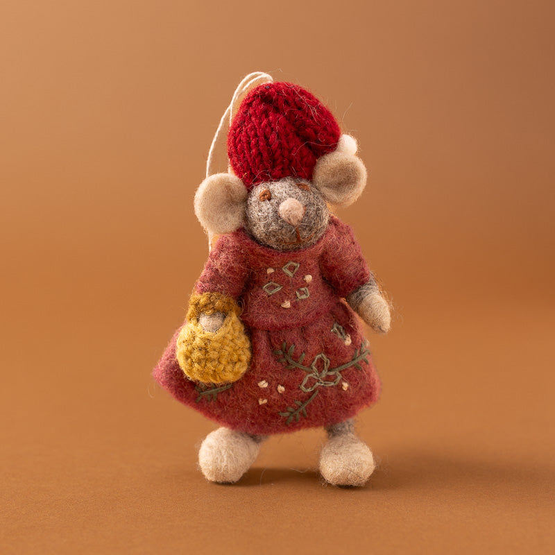 A felted wool mouse ornament wearing a red knit hat and pink dress with embroidered floral details, holding a yellow crocheted basket,