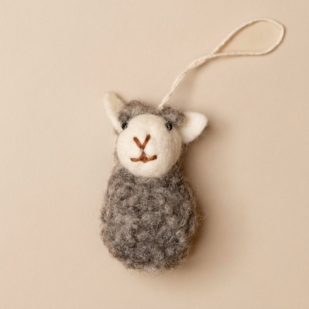 Felted sheep ornament on a beige background