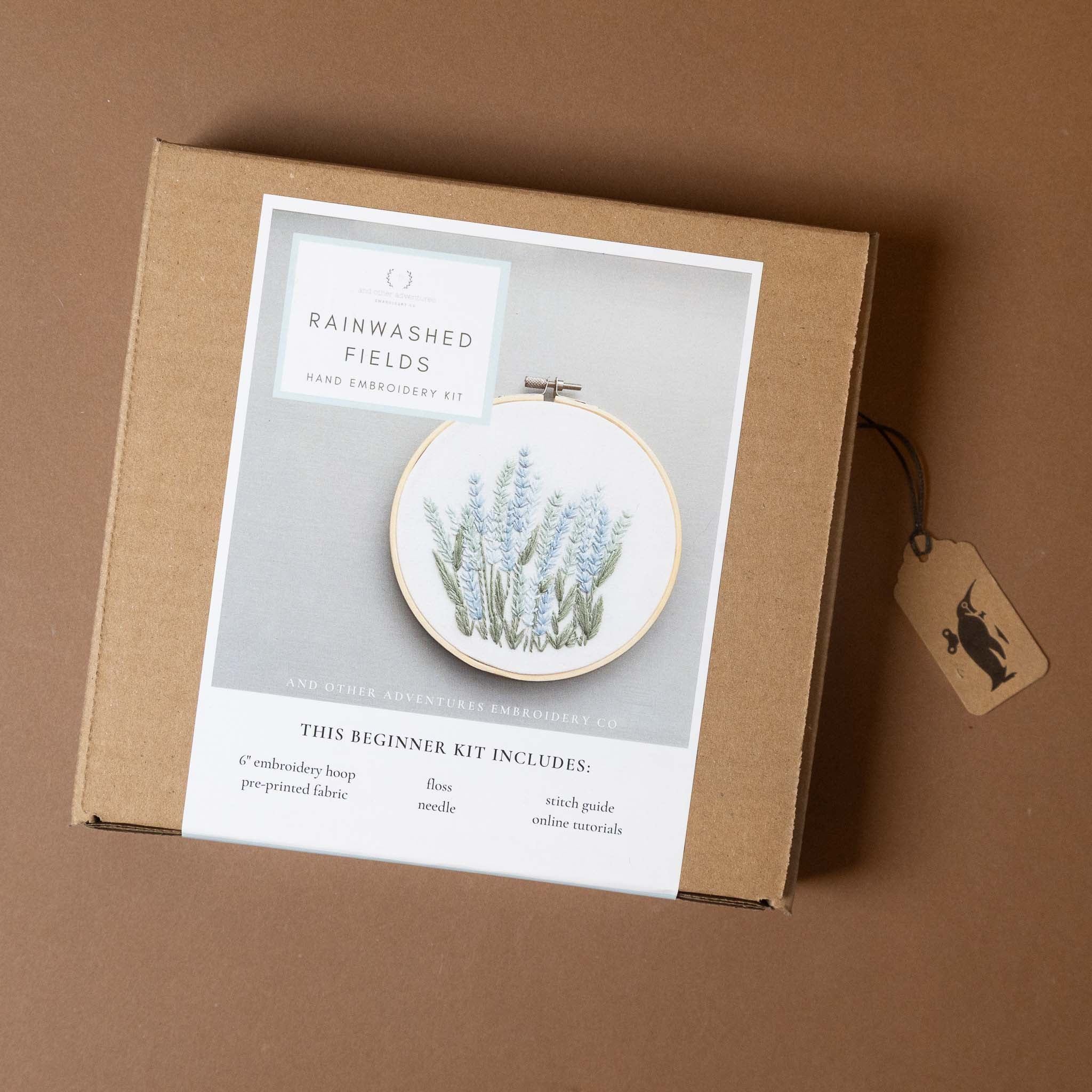 field-of-flowers-embroidery-kit-rainpackaging with an embroidered hoop on a brown background