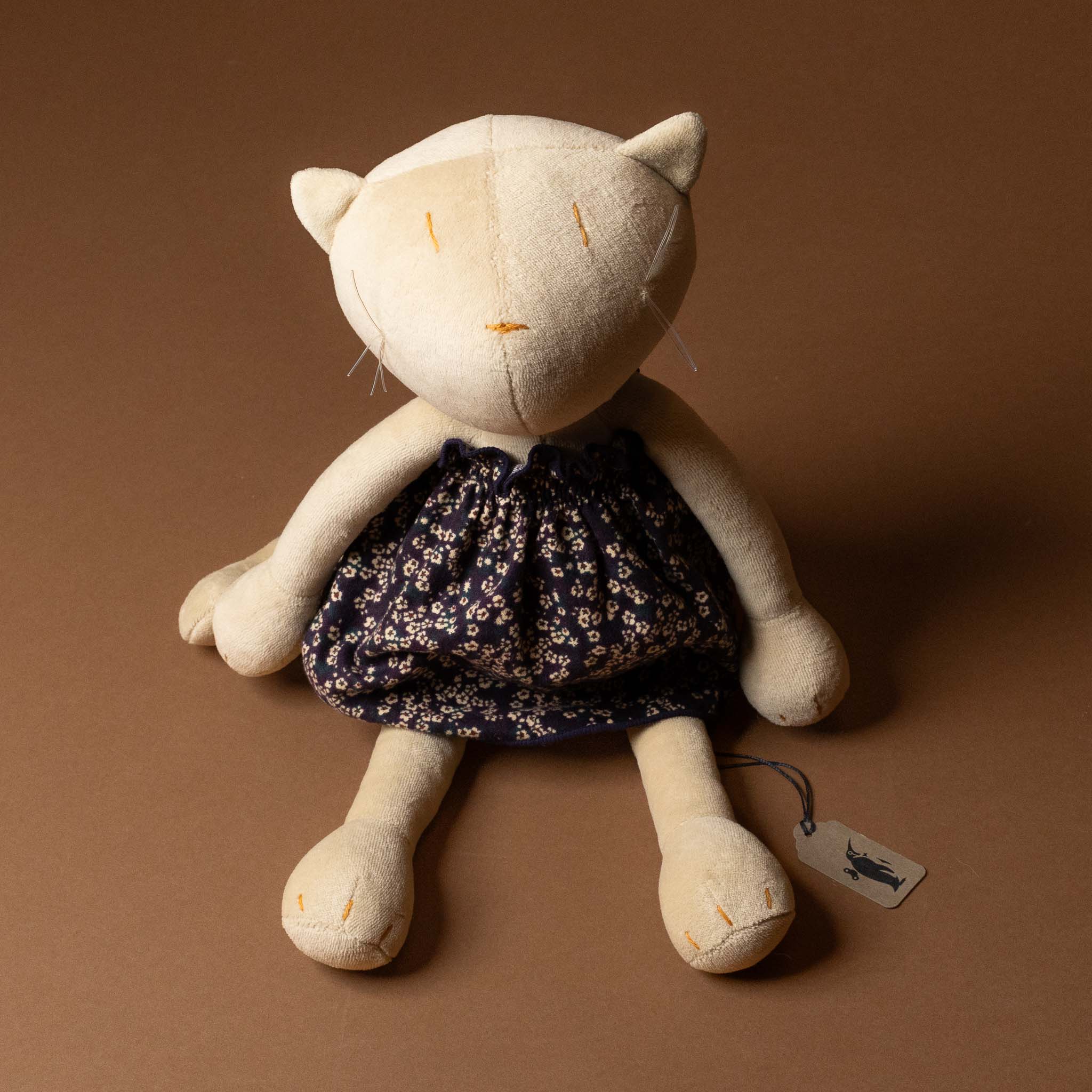 Stuffed cat toy with a grande-outfit-liberty-dress-midnight-floral on a brown background