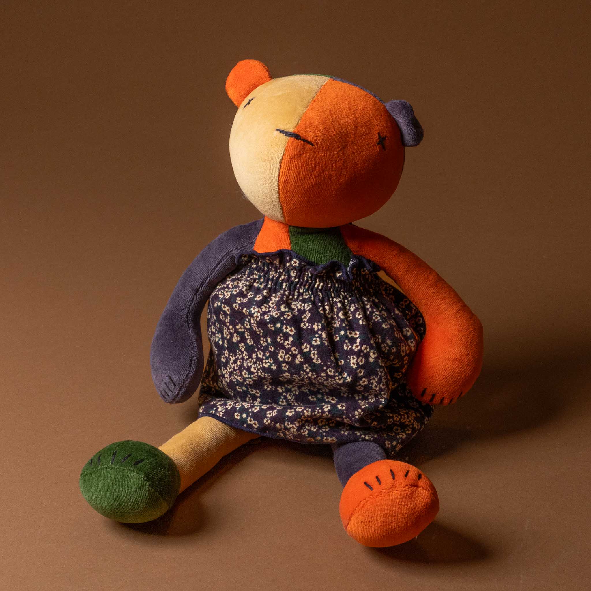 Stuffed toy with a patchwork design wearinggrande-outfit-liberty-dress-midnight-floral background
