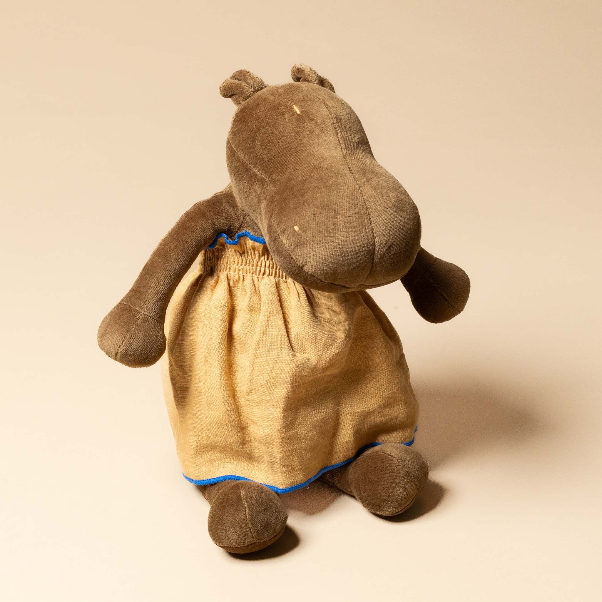 Brown stuffed animal wearing grande-outfit-linen-dress-ochre on a beige background