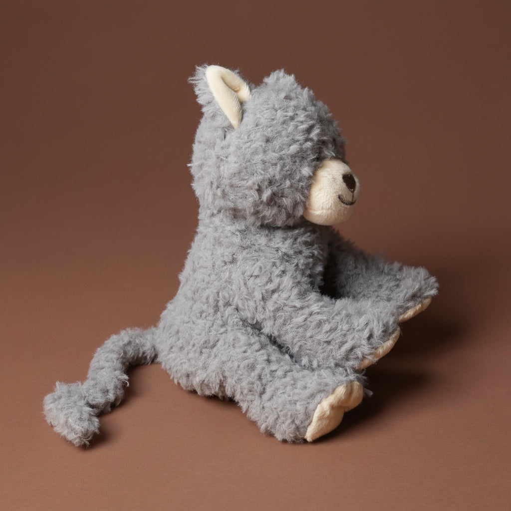 Gray plush grande-romy-the-cat--blueberry toy with a brown background