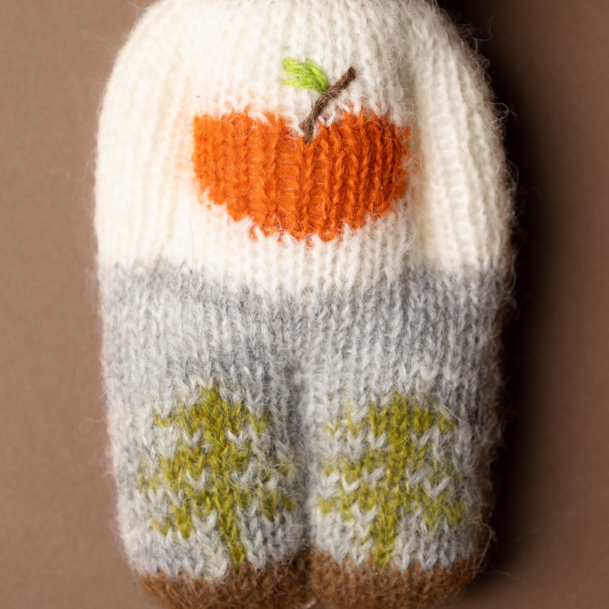 happy-go-lucky-bear Knitted baby bootie with apple nd green leaves on a brown background