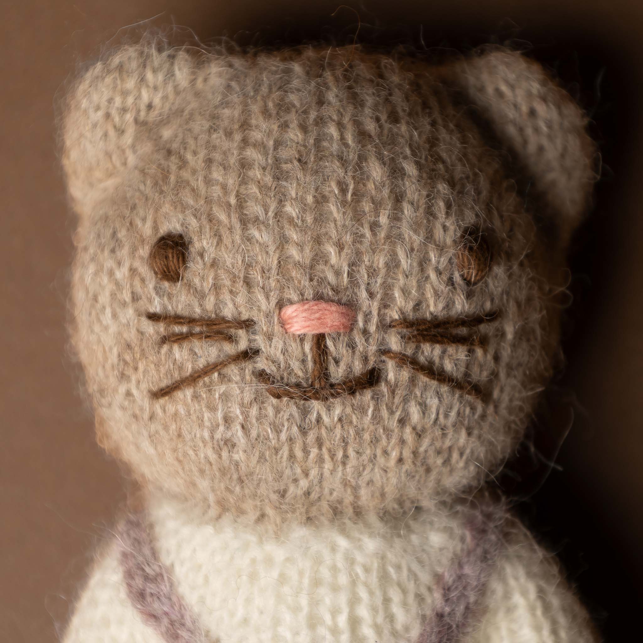 happy-go-lucky-cat Knitted cat toy with a brown face and white body on a dark background
