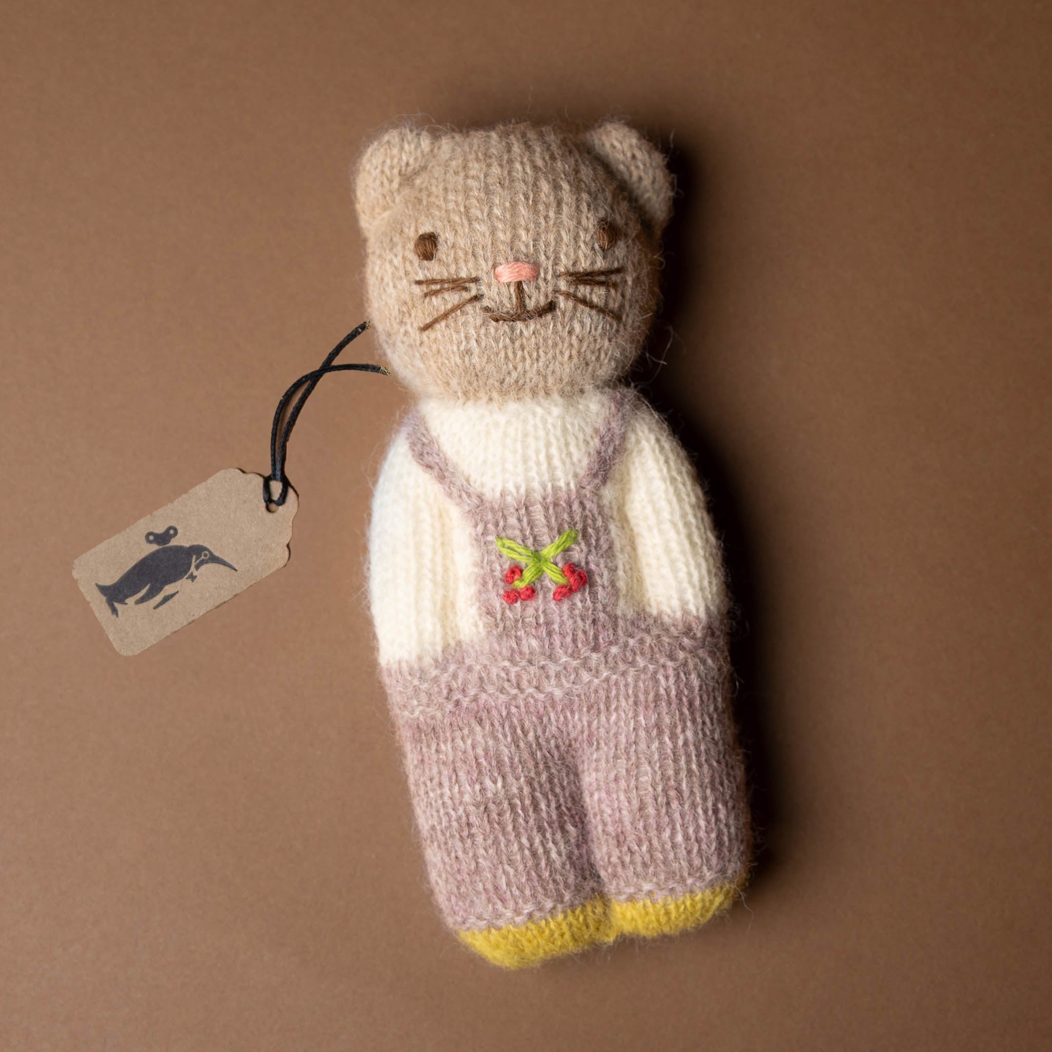happy-go-lucky-cat Knitted cat toy with a tag on a brown background