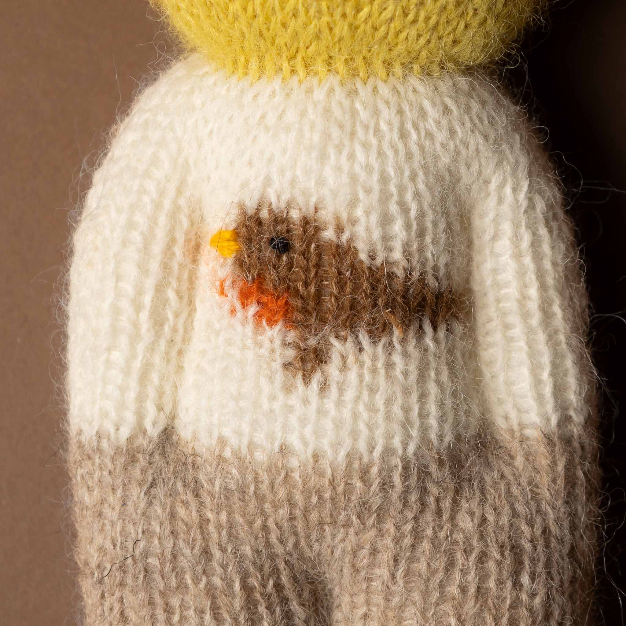 happy-go-lucky-duckie Knitted bird toy with a white body, brown wings, and yellow beak on a dark background