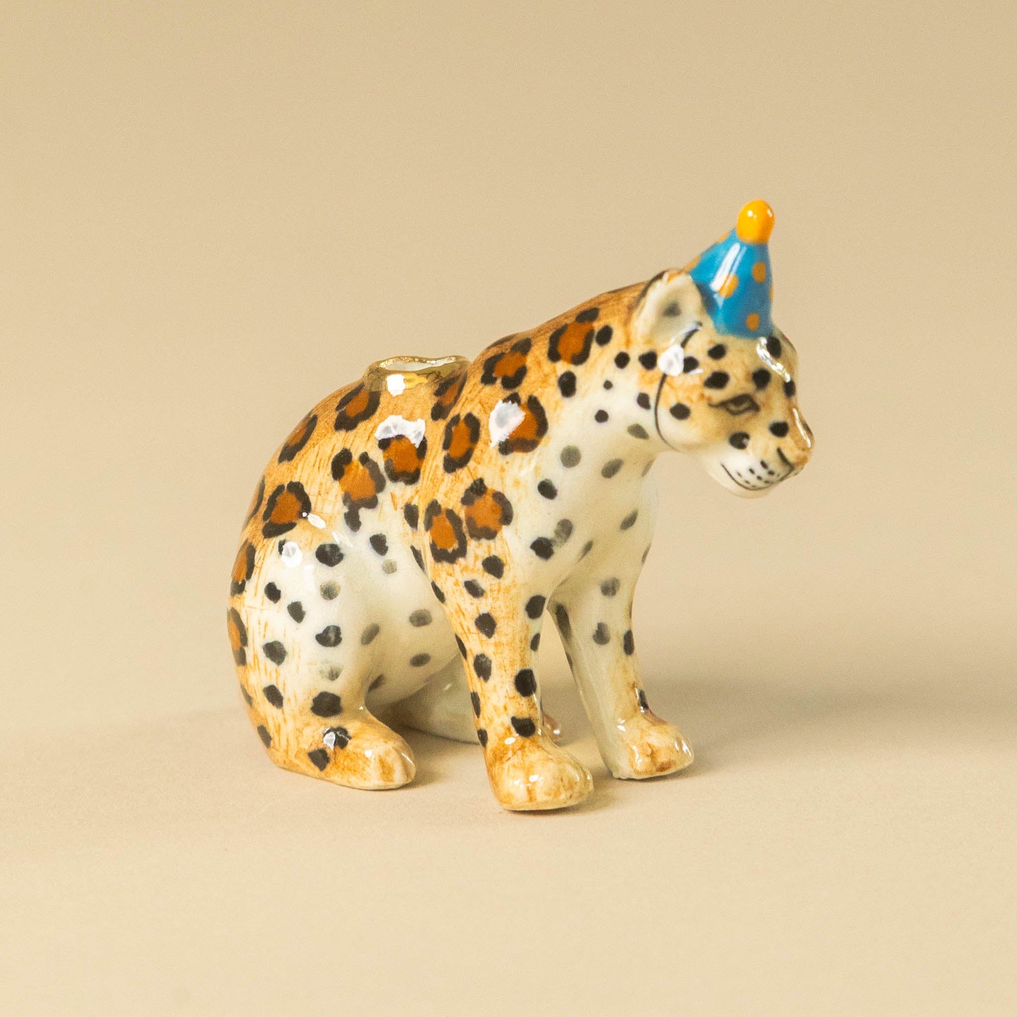 heirloom-porcelain-cake-topper-jaguar figurine wearing a party hat on a beige background