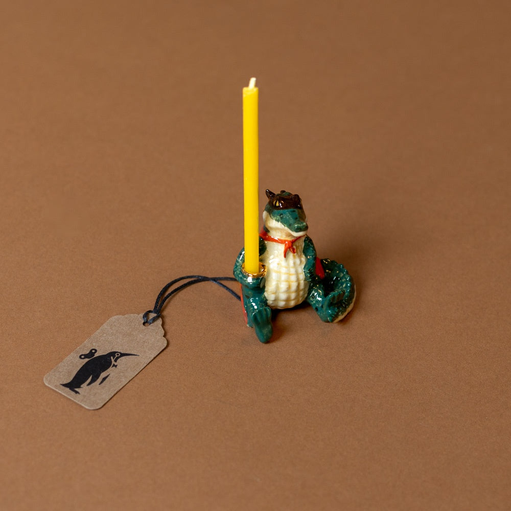 heirloom-porcelain-cake-topper-super-gator with a yellow candle on a brown background