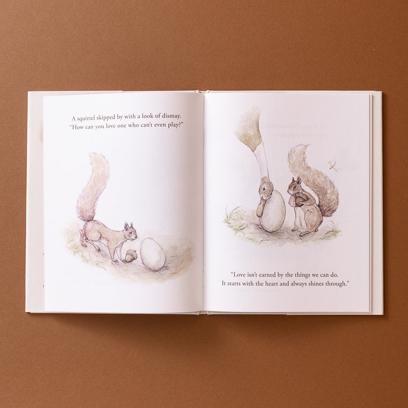 An open children's book laid flat on a warm brown background, showing two illustrated squirrel pages with printed text. The left page has a small squirrel beside an egg, and the right page shows two squirrels near the egg with a quote below.