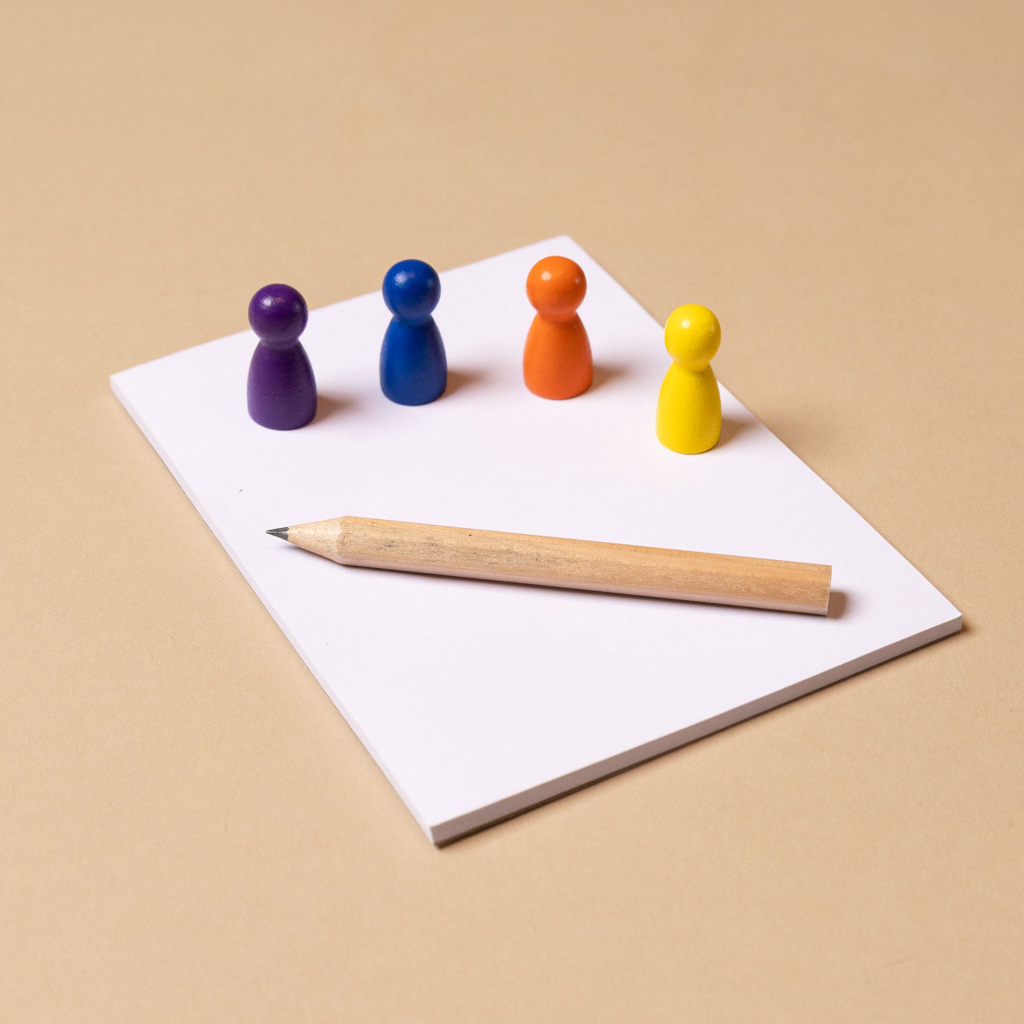 kids-vs-grown-ups-game-time Colorful wooden pegs and a pencil on a white sheet of paper with a beige background