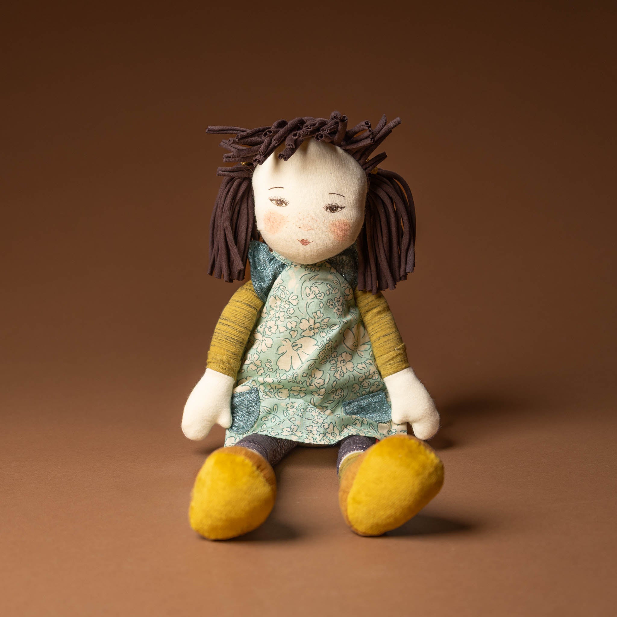 les-rosalie-rag-doll-iris with brown hair, floral dress, and yellow shoes on a brown background