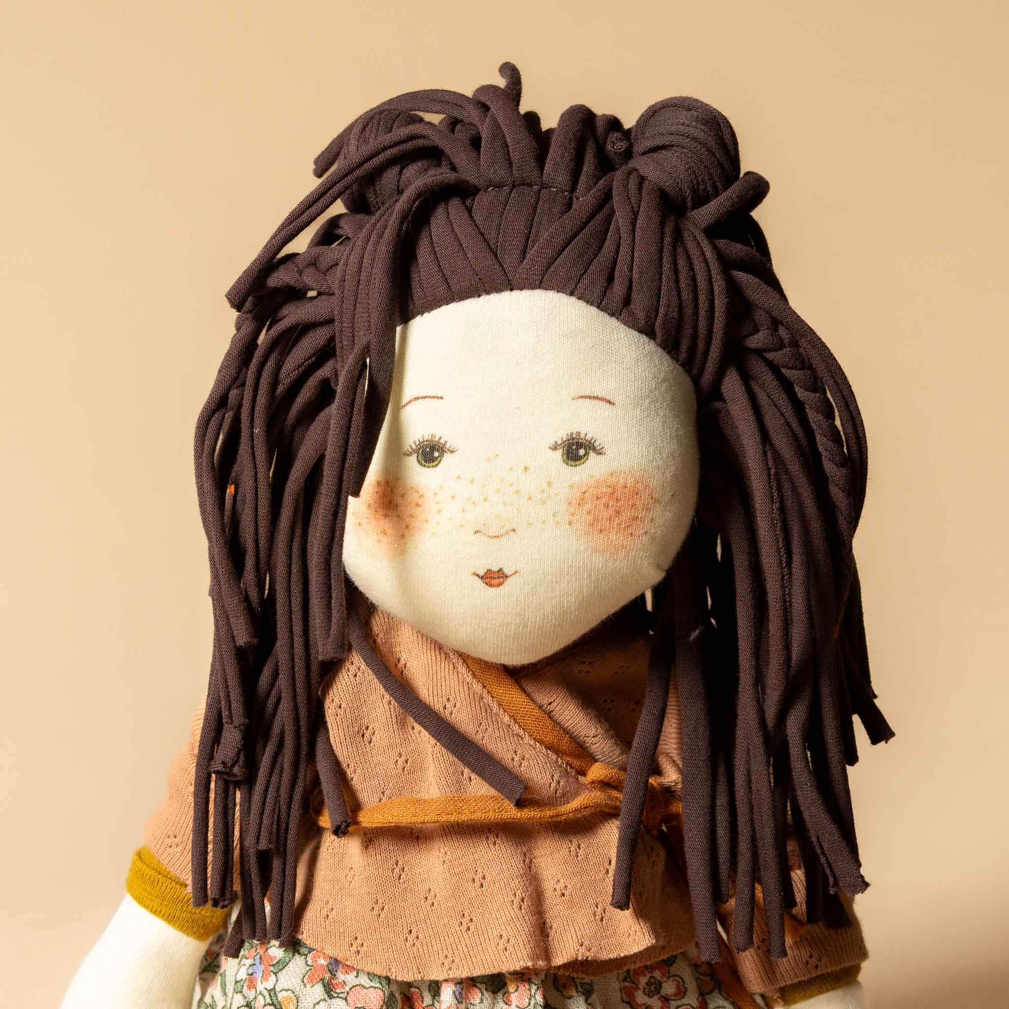 les-rosalie-rag-doll-marjolaine Textile doll with brown hair and a patterned outfit on a beige background