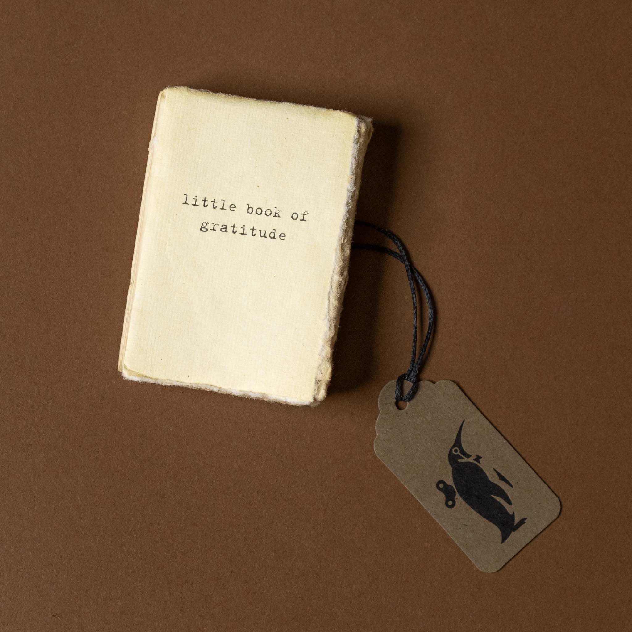 Small book titled 'little book of gratitude' with a tag on a brown background