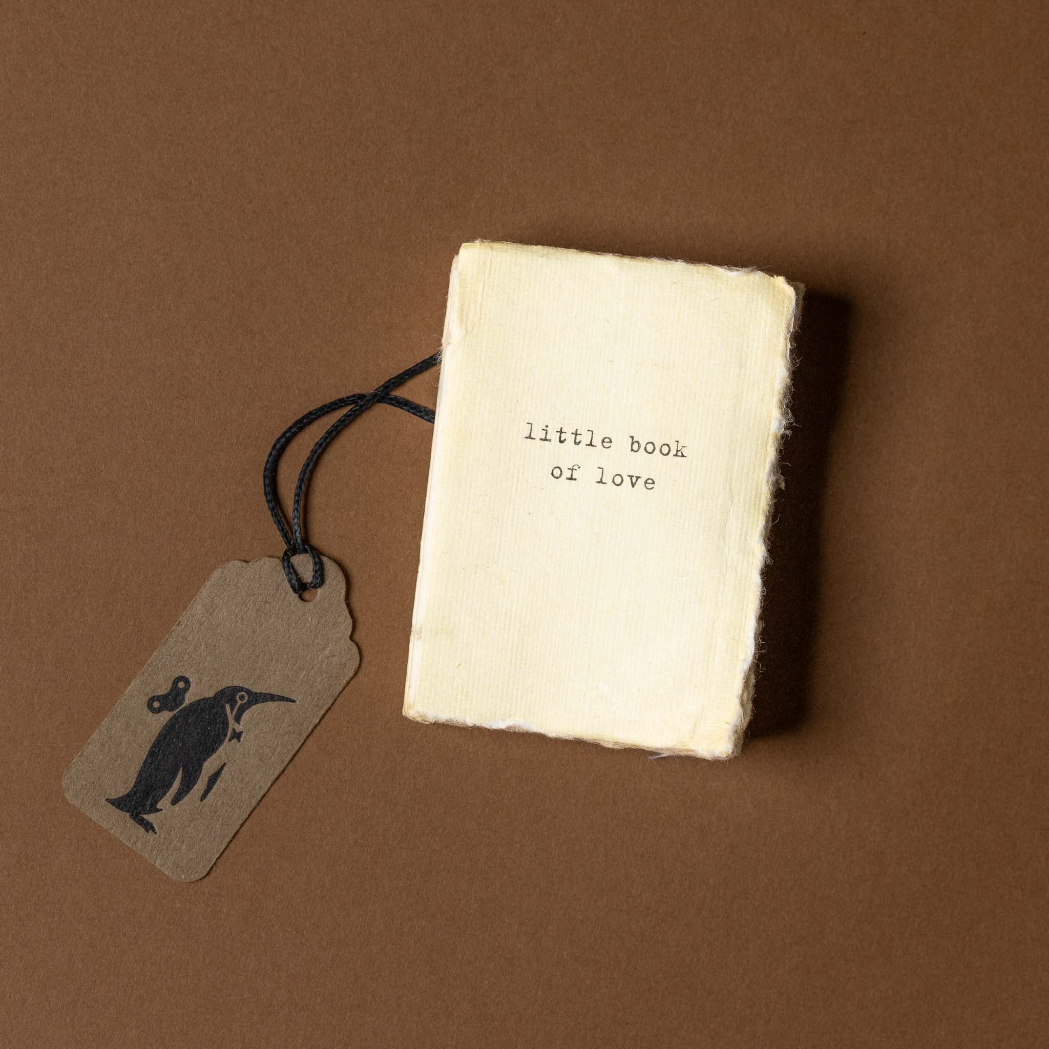 Small book titled 'little book of love' with a tag on a brown background