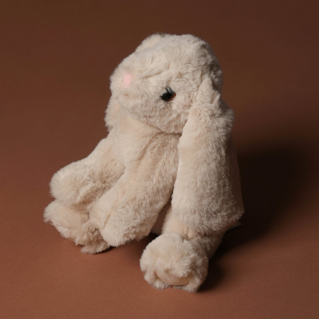Plush little-lottie-bunny-beige toy on a brown background