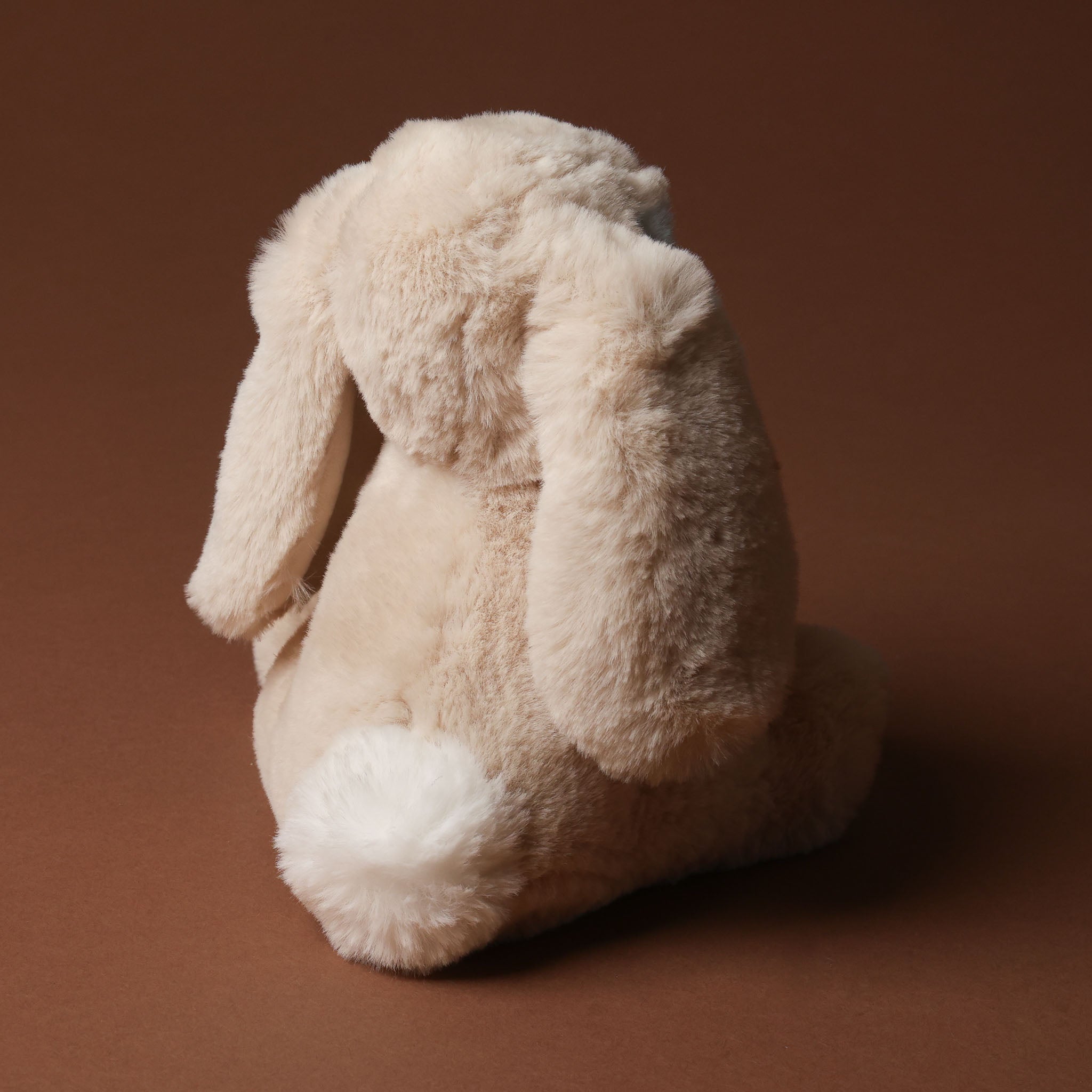 Beige plush little-lottie-bunny-beige toy on a brown background