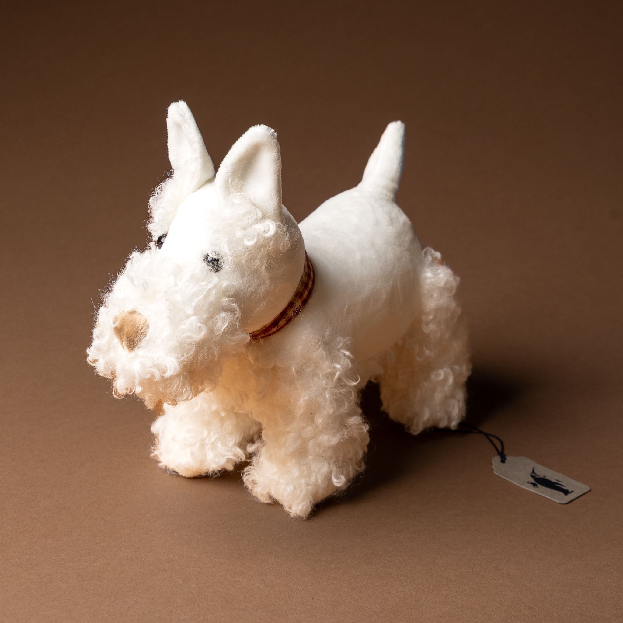 lola-the-dog White stuffed dog toy with a tag on a brown background