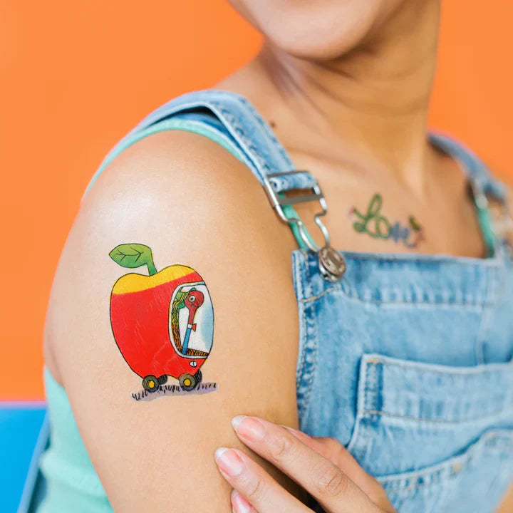 Person wearing a colorful lowly-apple-car-temporary-tattoo-pair tattoo on an orange background